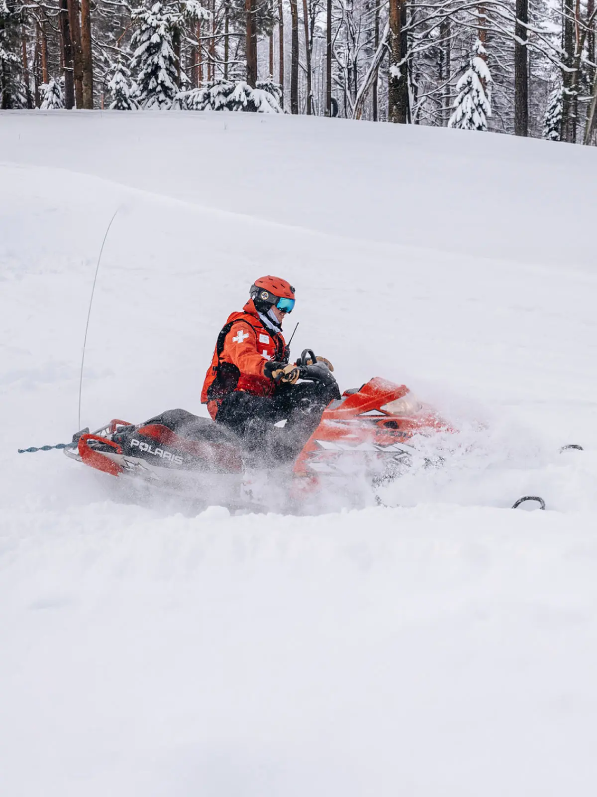 Ski patroller riding a snowmobile through powder at Soda Springs