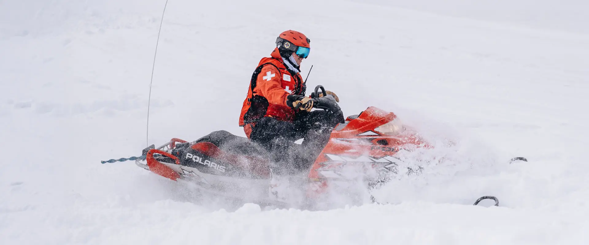 Ski patroller riding a snowmobile through powder at Soda Springs